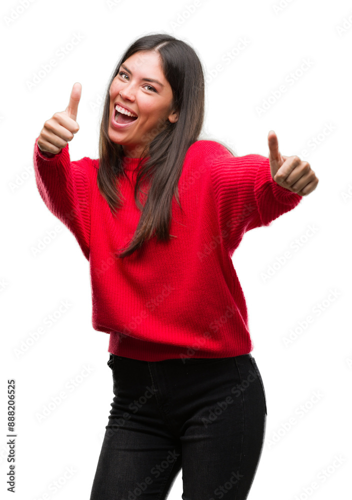 Young beautiful hispanic wearing red sweater approving doing positive gesture with hand, thumbs up smiling and happy for success. Looking at the camera, winner gesture. Young beautiful hispanic wearing red sweater approving doing positive gesture with hand, thumbs up smiling and happy for success. Looking at the camera, winner gesture.