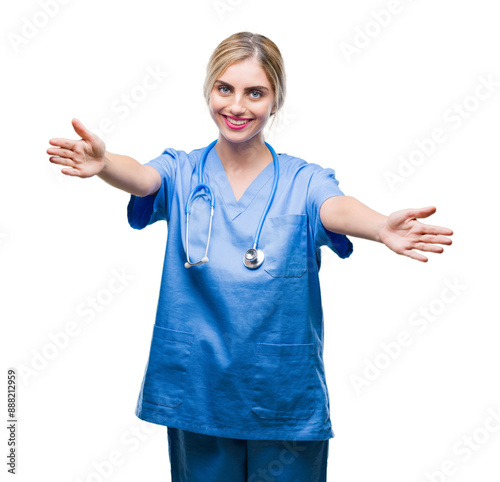 Young beautiful blonde doctor surgeon nurse woman over isolated background looking at the camera smiling with open arms for hug. Cheerful expression embracing happiness.