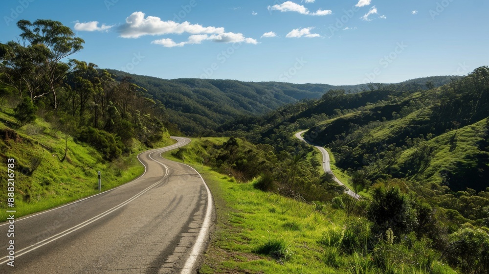 A winding mountain road cutting through lush, green hills. The road twists and turns, offering stunning views of the landscape below, with a clear blue sky overhead. A winding mountain road cutting through lush, green hills. The road twists and turns, offering stunning views of the landscape below, with a clear blue sky overhead.
