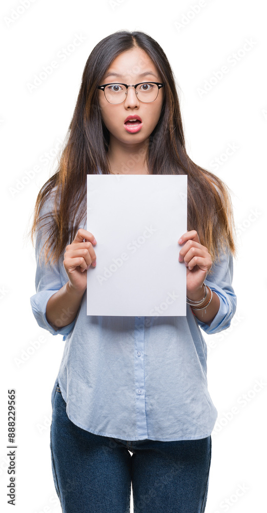 Young asian woman holding blank paper over isolated background scared in shock with a surprise face, afraid and excited with fear expression Young asian woman holding blank paper over isolated background scared in shock with a surprise face, afraid and excited with fear expression