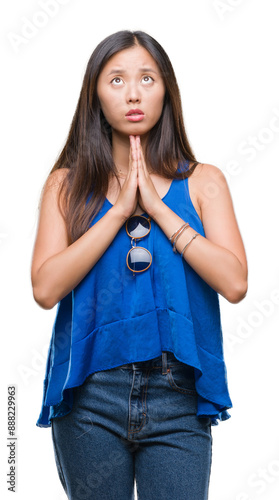 Young asian woman over isolated background begging and praying with hands together with hope expression on face very emotional and worried. Asking for forgiveness. Religion concept.