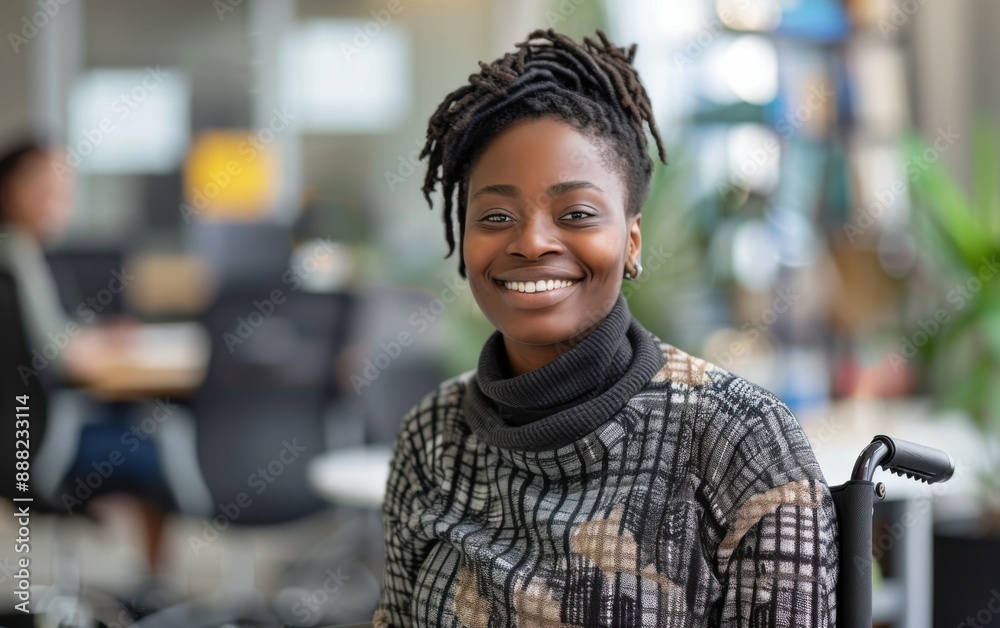 A Black woman with dreadlocks smiles while sitting in a wheelchair in an office setting A Black woman with dreadlocks smiles while sitting in a wheelchair in an office setting