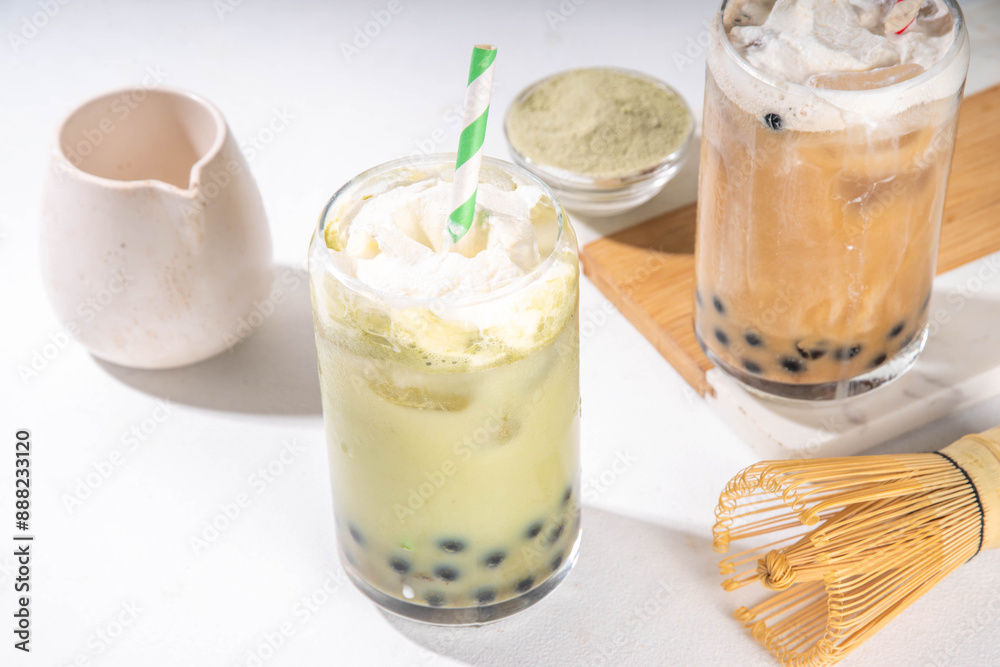 Classic and green matcha boba bubble tea with tapioca pearls and whipped non-dairy creamer on top of glass, summer cold sweet dessert drink on white table background copy space Classic and green matcha boba bubble tea with tapioca pearls and whipped non-dairy creamer on top of glass, summer cold sweet dessert drink on white table background copy space