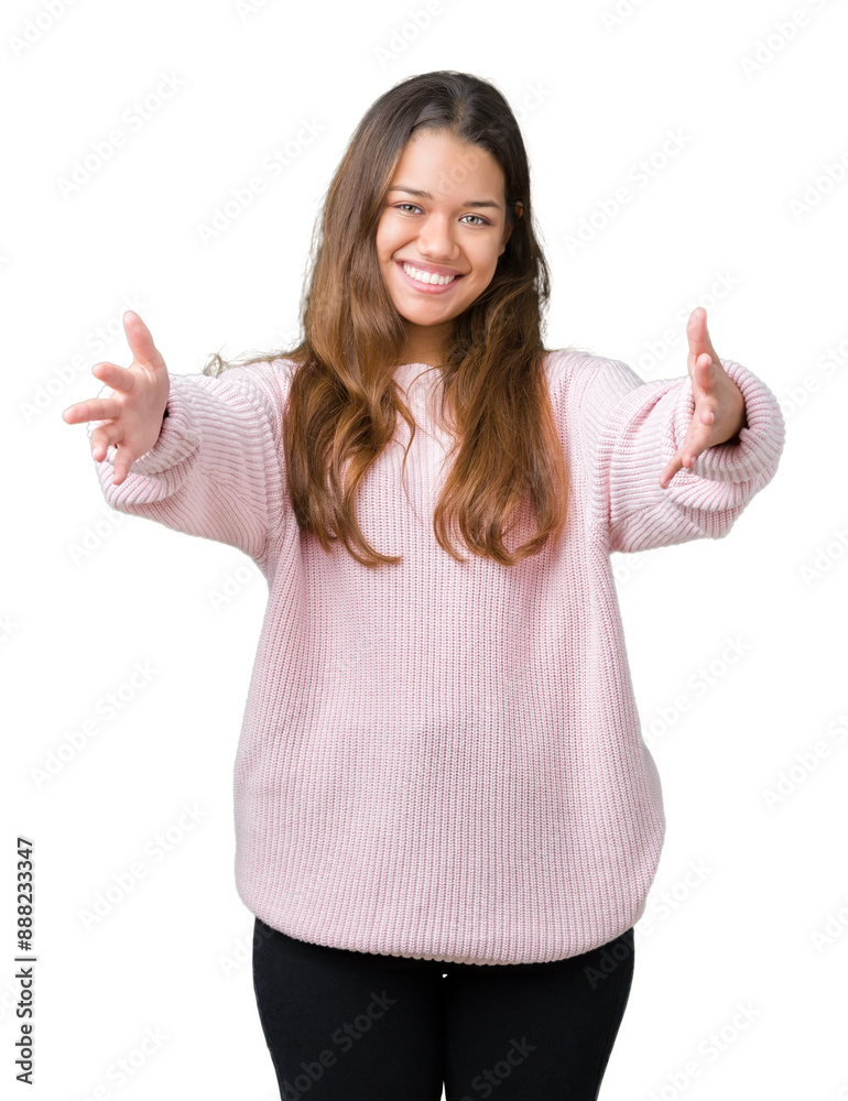 Young beautiful brunette woman wearing pink winter sweater over isolated background looking at the camera smiling with open arms for hug. Cheerful expression embracing happiness. Young beautiful brunette woman wearing pink winter sweater over isolated background looking at the camera smiling with open arms for hug. Cheerful expression embracing happiness.