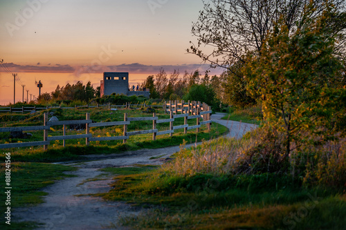 A winding path leading into the sunset through an observation tower made from an old building. Hiking trail in Paljassaare, Tallinn,  Estonia. photo