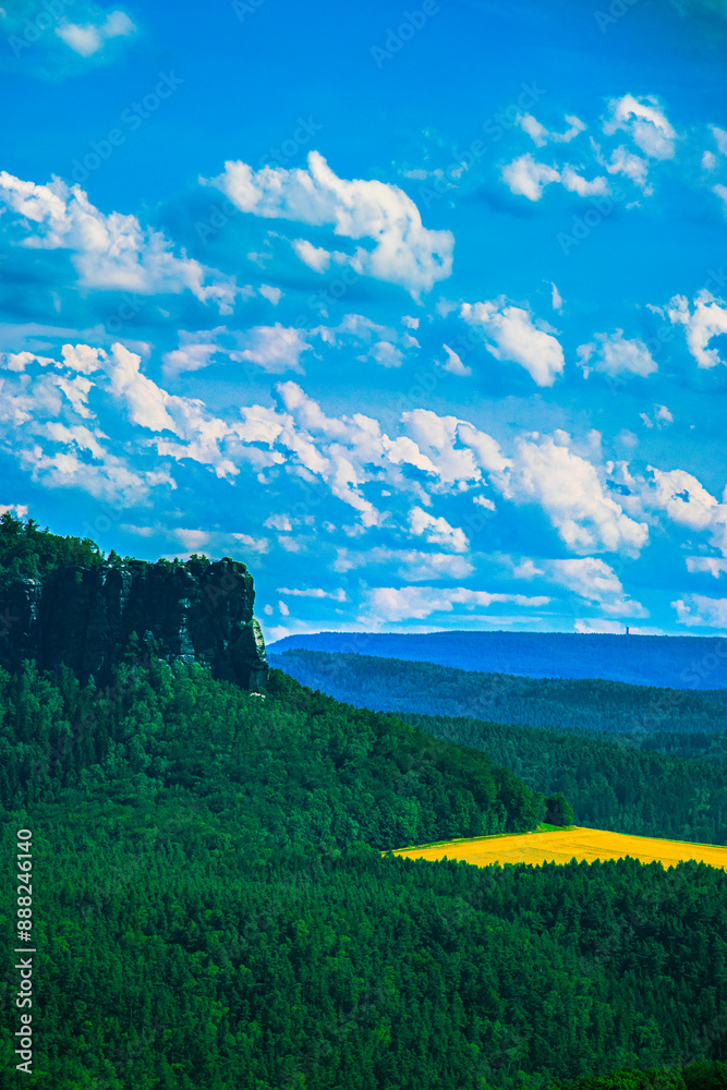 Obraz premium a narrow river flows in the mountains, many green trees, blue sky, clouds