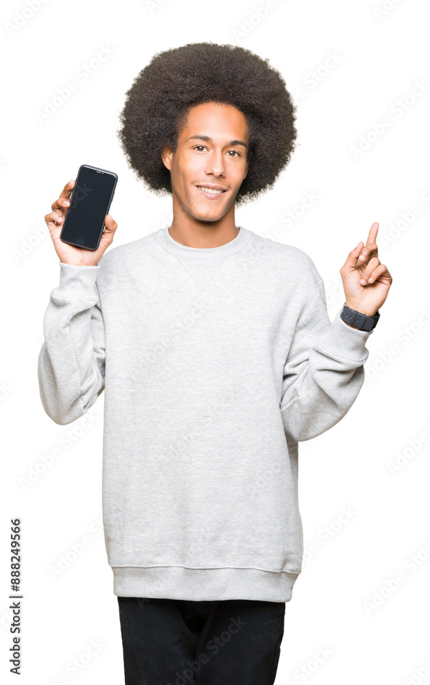 Young african american man with afro hair showing smartphone screen very happy pointing with hand and finger to the side Young african american man with afro hair showing smartphone screen very happy pointing with hand and finger to the side