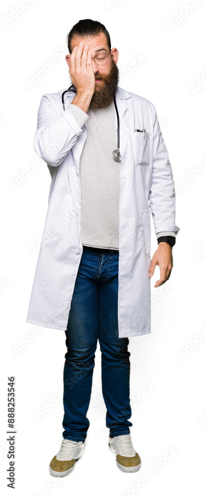 Young blond doctor man with beard wearing medical coat Yawning tired covering half face, eye and mouth with hand. Face hurts in pain.