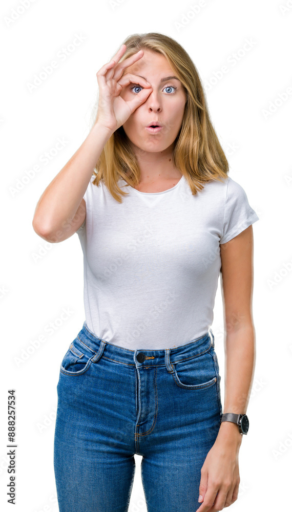 Fototapeta premium Beautiful young woman wearing casual white t-shirt over isolated background doing ok gesture shocked with surprised face, eye looking through fingers. Unbelieving expression.