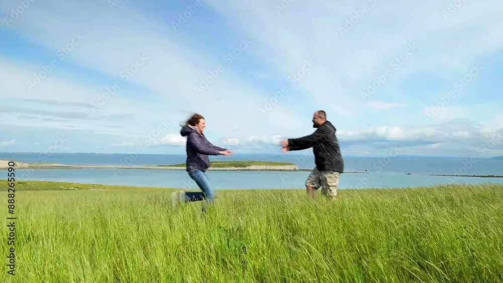 Man and woman hiking on top of green hill by ocean and having fun, adventure and lifestyle, outdoor activities, Silverstrand, Galway, Ireland, 4k Man and woman hiking on top of green hill by ocean and having fun, adventure and lifestyle, outdoor activities, Silverstrand, Galway, Ireland, 4k
