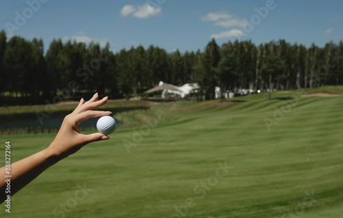 Closeup of golf ball being held in woman hand on sunny day on golf course