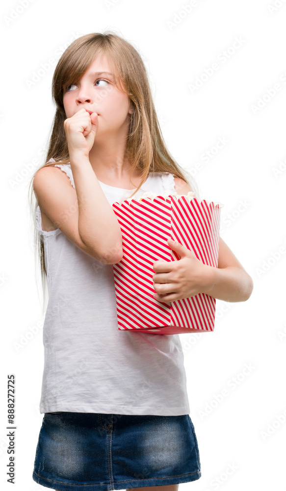 Young blonde toddler holding popcorn pack serious face thinking about question, very confused idea Young blonde toddler holding popcorn pack serious face thinking about question, very confused idea