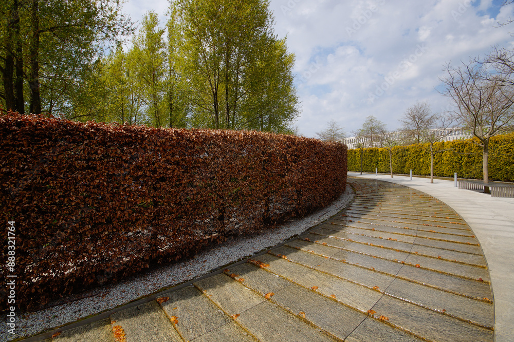 City park Krasnodar. An artificial fast-flowing river with granite banks flows around an evergreen hedge with a seating area. Public landscape Galitsky Park for recreation and walks