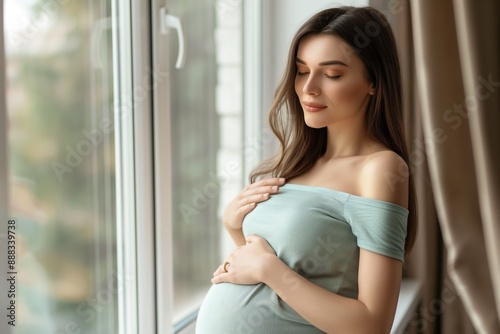 Free Download Pregnant woman standing by the window, relaxing and gently holding her belly, awaiting motherhood, peaceful and serene atmosphere, expectant mother concept - GFXLoad