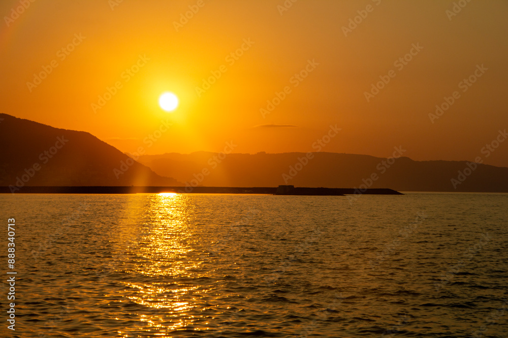 A serene sunset over the mountains reflects golden hues on the water. The vibrant orange and yellow sky creates a peaceful, captivating scene as the sun dips below the horizon. A serene sunset over the mountains reflects golden hues on the water. The vibrant orange and yellow sky creates a peaceful, captivating scene as the sun dips below the horizon.