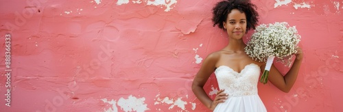 Bride Posing Against Pink Wall With White Flowers