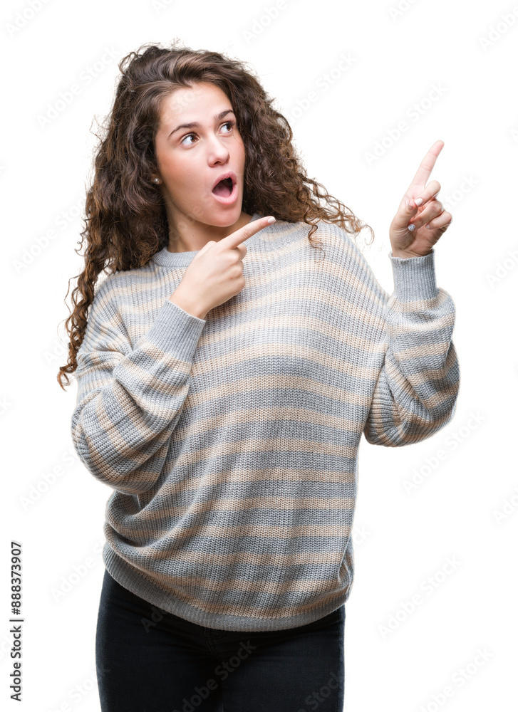 Beautiful brunette curly hair young girl wearing winter sweater over isolated background smiling and looking at the camera pointing with two hands and fingers to the side.