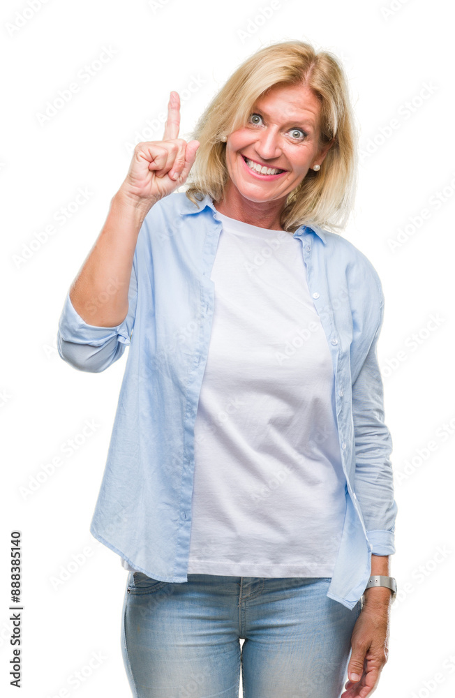 Middle age blonde woman over isolated background pointing finger up with successful idea. Exited and happy. Number one. Middle age blonde woman over isolated background pointing finger up with successful idea. Exited and happy. Number one.