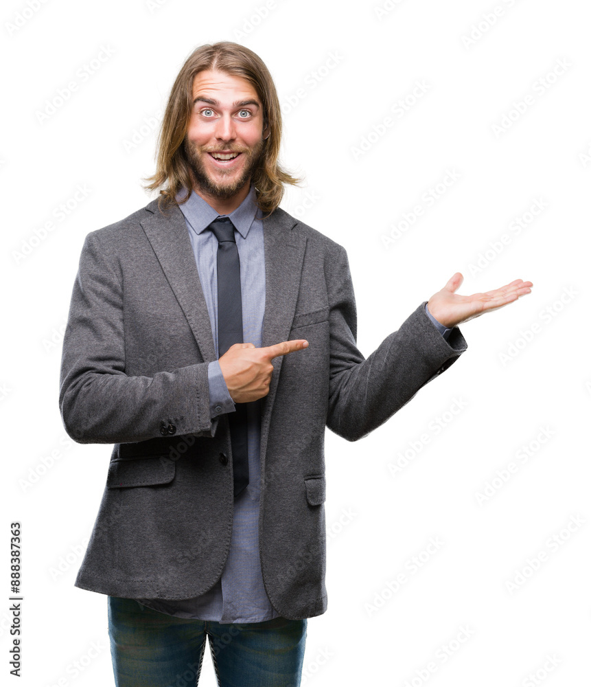 Young handsome business man with long hair over isolated background amazed and smiling to the camera while presenting with hand and pointing with finger. Young handsome business man with long hair over isolated background amazed and smiling to the camera while presenting with hand and pointing with finger.