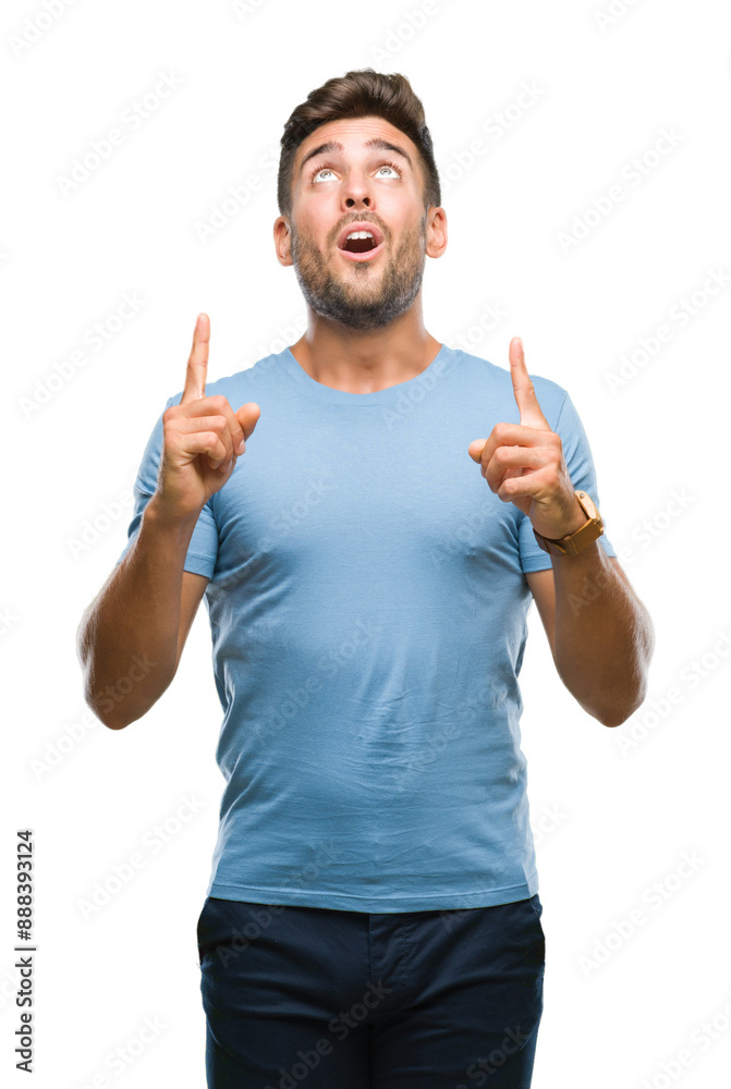 Young handsome man over isolated background amazed and surprised looking up and pointing with fingers and raised arms. Young handsome man over isolated background amazed and surprised looking up and pointing with fingers and raised arms.