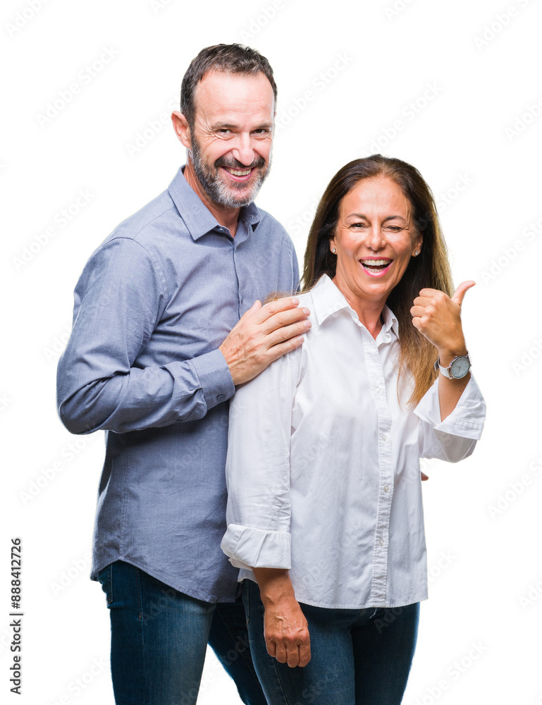 Middle age hispanic business couple over isolated background smiling with happy face looking and pointing to the side with thumb up. Middle age hispanic business couple over isolated background smiling with happy face looking and pointing to the side with thumb up.