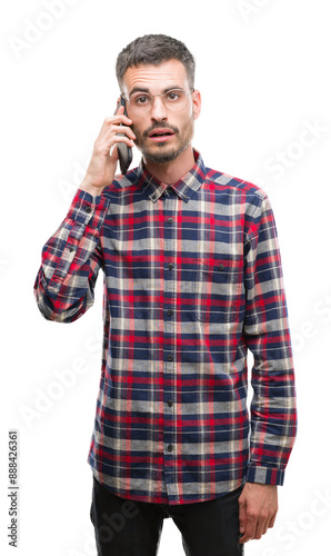 Young hipster adult man talking on the phone scared in shock with a surprise face, afraid and excited with fear expression