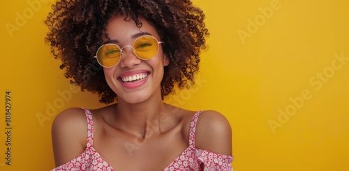 Woman With Curly Hair Laughing In Sunglasses Against Yellow Wall