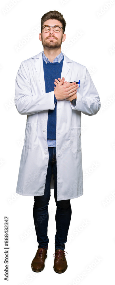 Young handsome scientist man wearing glasses smiling with hands on chest with closed eyes and grateful gesture on face. Health concept. Young handsome scientist man wearing glasses smiling with hands on chest with closed eyes and grateful gesture on face. Health concept.