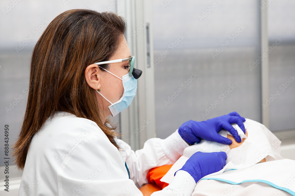 Naklejka premium Dermatologist carrying out a skin biopsy on the face of a senior adult patient. Application of anesthesia.