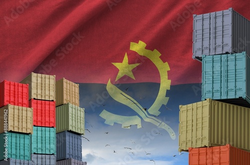 Angola flag and big stack of shipping cargo containers in docks with sky background close up photo