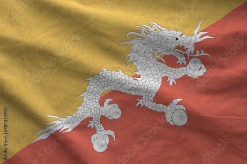 Bhutan flag depicted on folded wavy fabric of old cloth close up photo