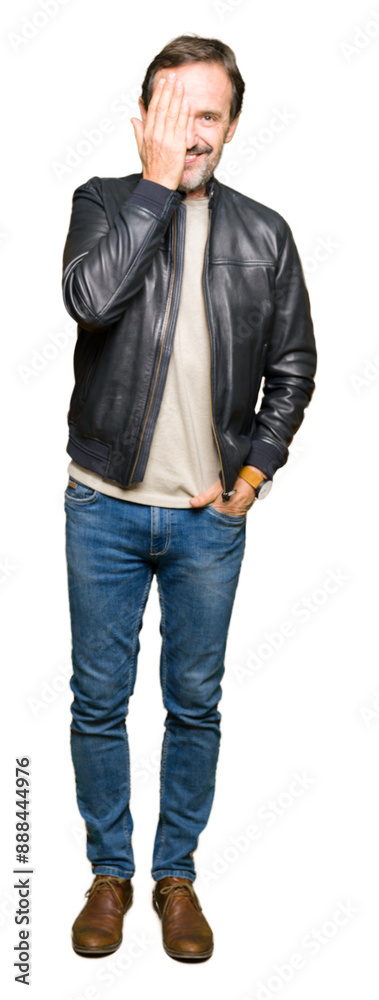 Middle age handsome man wearing black leather jacket covering one eye with hand with confident smile on face and surprise emotion. Middle age handsome man wearing black leather jacket covering one eye with hand with confident smile on face and surprise emotion.