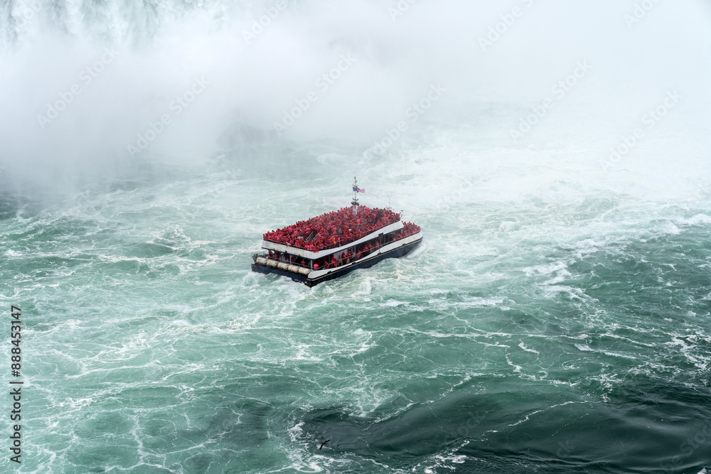 Naklejka premium A tour boat cruises towards to mist at the base of the Horseshoe Falls in Niagara Falls Ontario.