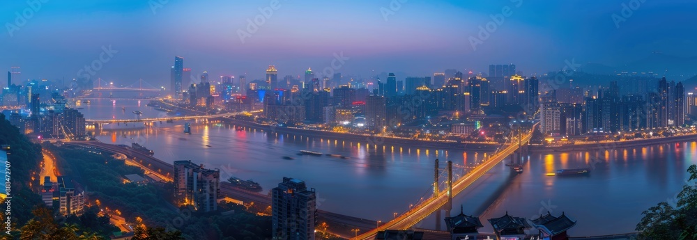 Naklejka premium Cityscape at Dusk with River and Bridge