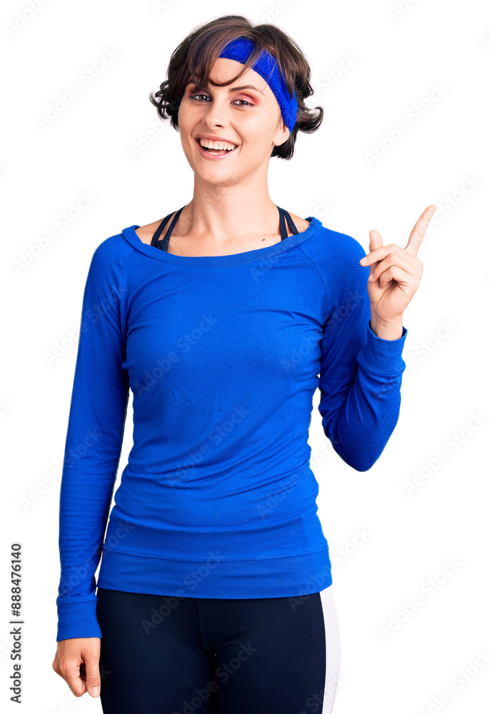 Beautiful young woman with short hair wearing training workout clothes pointing finger up with successful idea. exited and happy. number one. Beautiful young woman with short hair wearing training workout clothes pointing finger up with successful idea. exited and happy. number one.