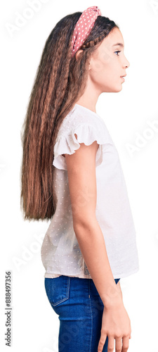 Cute hispanic child girl wearing casual white tshirt looking to side, relax profile pose with natural face and confident smile.