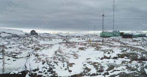 Snow covered Antarctica rocky coast island, aerial view Vernadsky science base polar station. Antarctic expeditions and travel, exploration. People explore South Pole wild nature. Aerial drone flight
