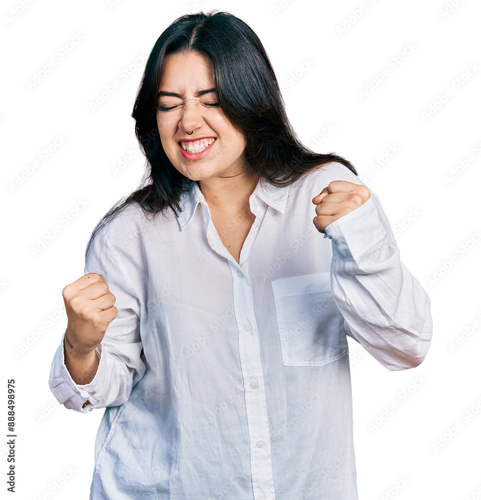 Beautiful hispanic woman wearing casual white shirt very happy and excited doing winner gesture with arms raised, smiling and screaming for success. celebration concept. Beautiful hispanic woman wearing casual white shirt very happy and excited doing winner gesture with arms raised, smiling and screaming for success. celebration concept.
