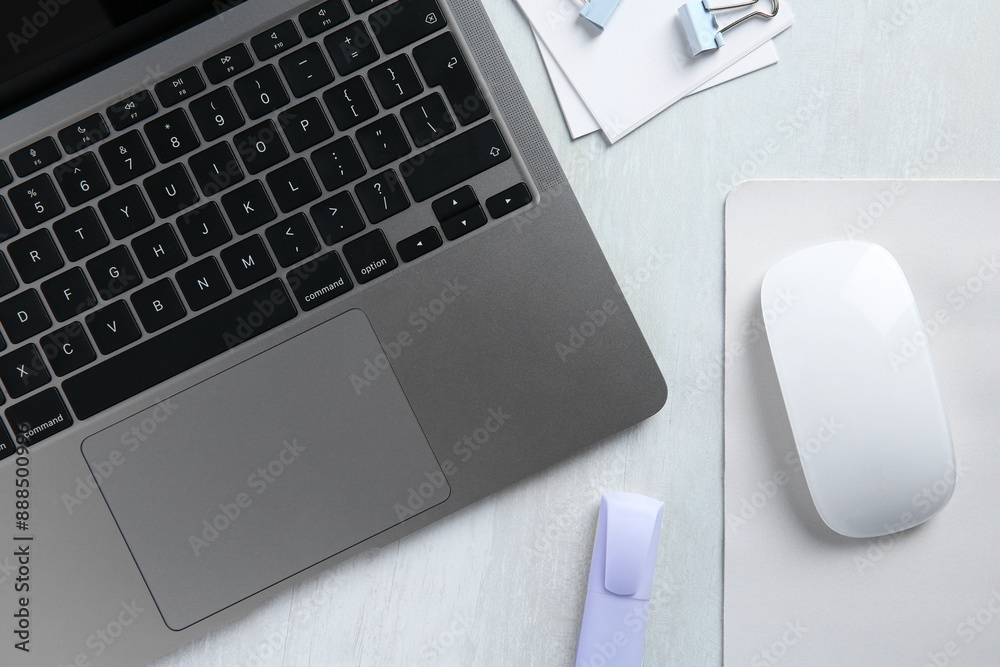 Wireless mouse with mousepad, stationery and laptop on light wooden table, flat lay Wireless mouse with mousepad, stationery and laptop on light wooden table, flat lay