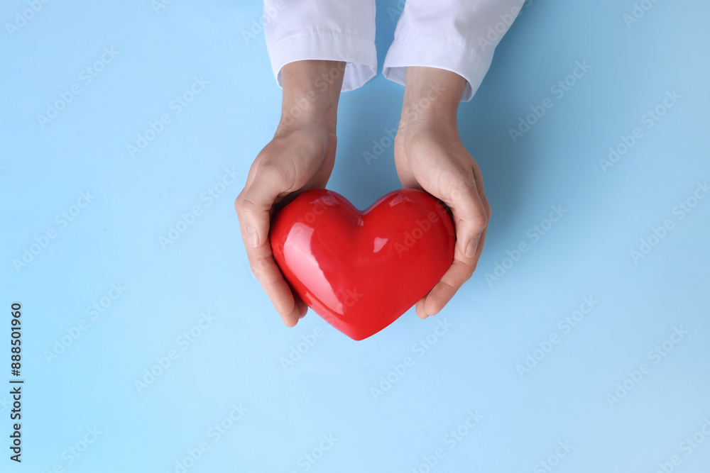 Doctor holding red heart on light blue background, top view Doctor holding red heart on light blue background, top view