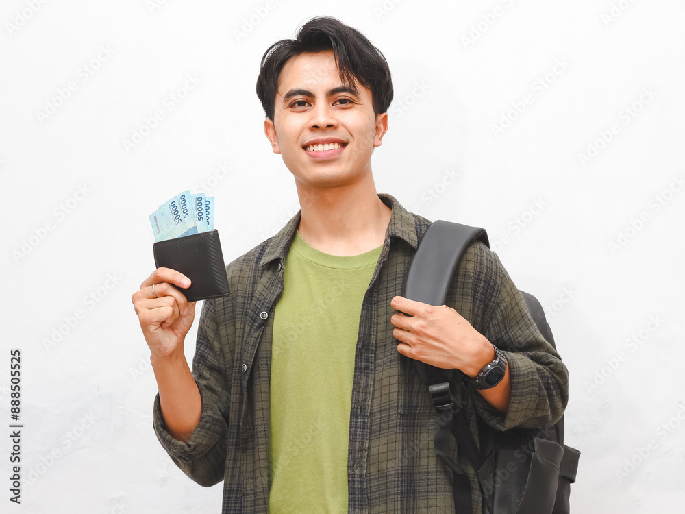 Happy Asian male student in green flannel shirt posing while holding wallet filled with money on white background Happy Asian male student in green flannel shirt posing while holding wallet filled with money on white background