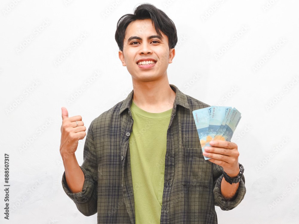 happy Asian man in green flannel shirt posing hold money against white background happy Asian man in green flannel shirt posing hold money against white background