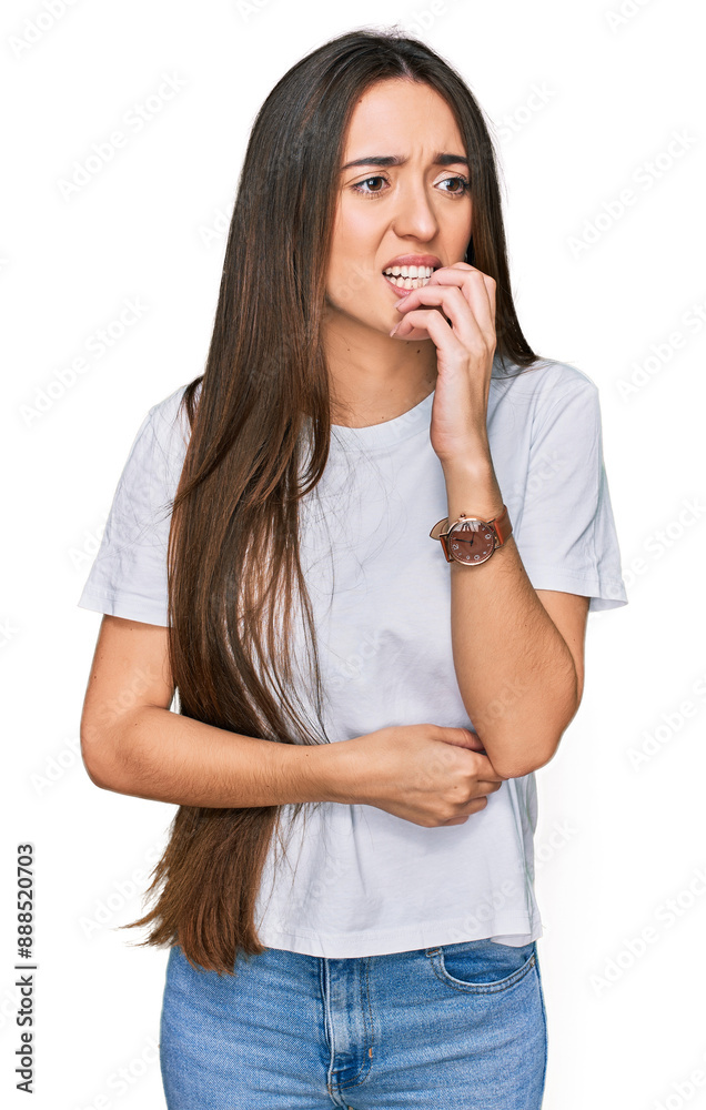 Young hispanic girl wearing casual white t shirt looking stressed and nervous with hands on mouth biting nails. anxiety problem. Young hispanic girl wearing casual white t shirt looking stressed and nervous with hands on mouth biting nails. anxiety problem.