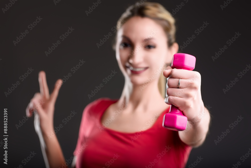 Young woman holding dumbbell is smiling at gym Young woman holding dumbbell is smiling at gym