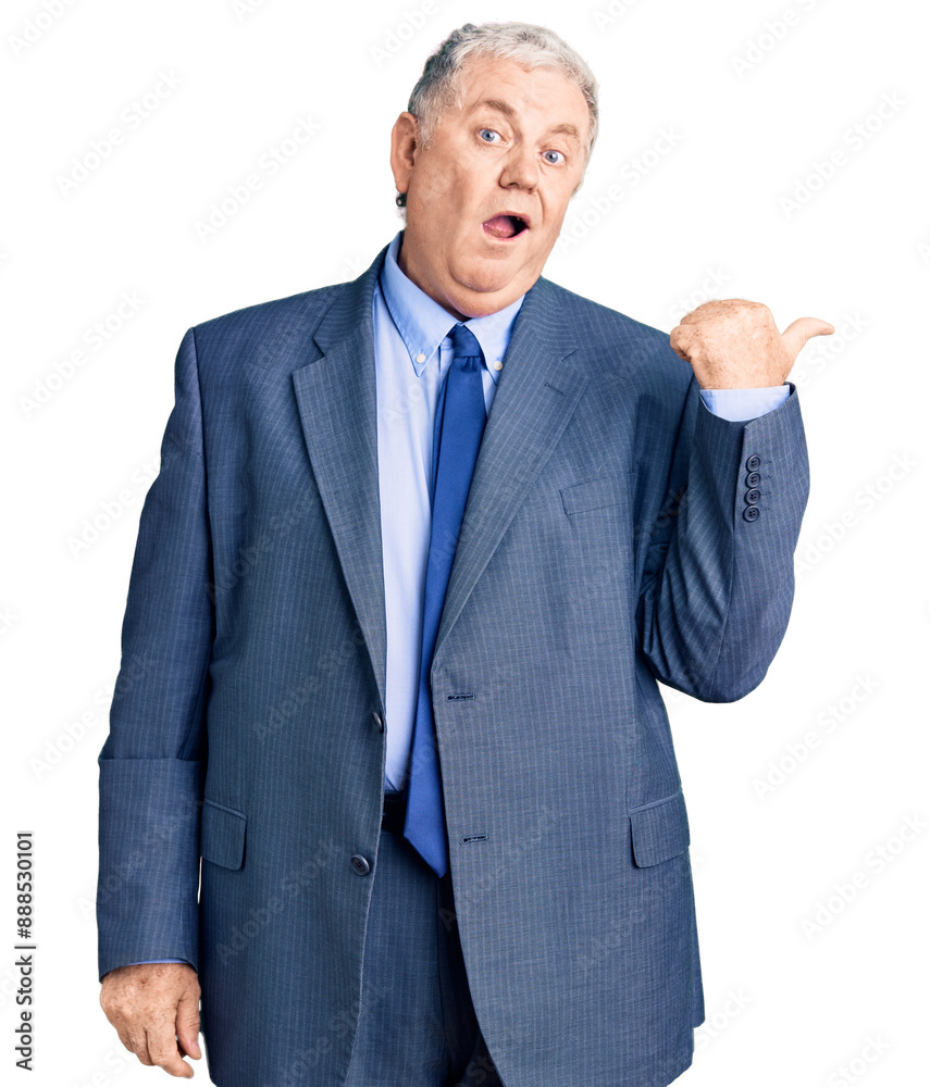 Senior grey-haired man wearing business jacket surprised pointing with hand finger to the side, open mouth amazed expression. Senior grey-haired man wearing business jacket surprised pointing with hand finger to the side, open mouth amazed expression.