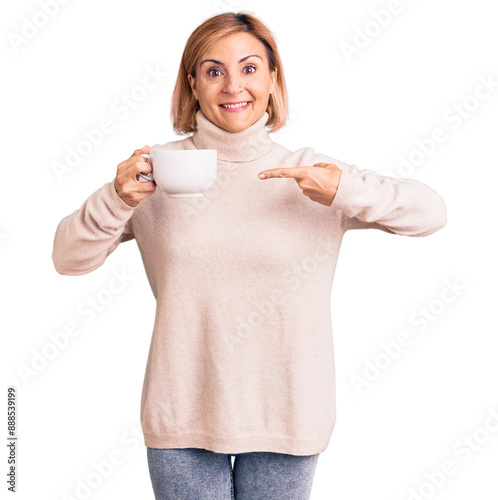 Young blonde woman holding coffee smiling happy pointing with hand and finger