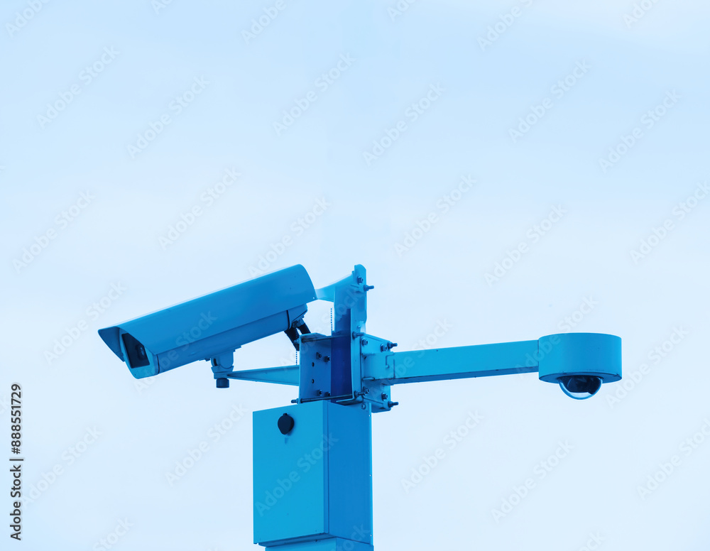 A security camera is securely attached to a tall metal pole, monitoring the area for safety and surveillance purposes. A security camera is securely attached to a tall metal pole, monitoring the area for safety and surveillance purposes.