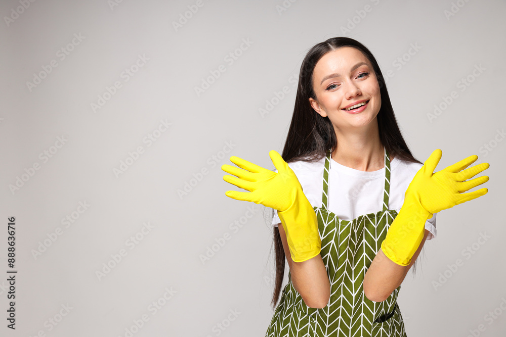Smiling young woman with gloved hands on gray background, space for text Smiling young woman with gloved hands on gray background, space for text