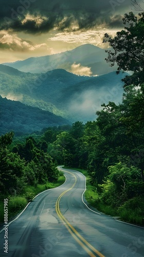 Countryside asphalt road surrounded by green foliage and rolling mountains