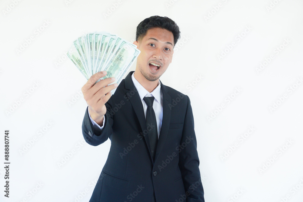 Adult Asian man wearing black suit and tie holding paper money while showing happy face expression Adult Asian man wearing black suit and tie holding paper money while showing happy face expression